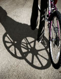young kid holding bike and the shadow is an older man in a wheelchair
