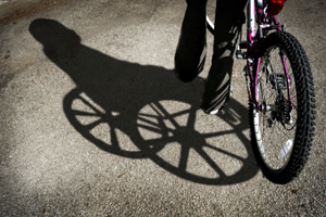young kid holding bike and the shadow is an older man in a wheelchair